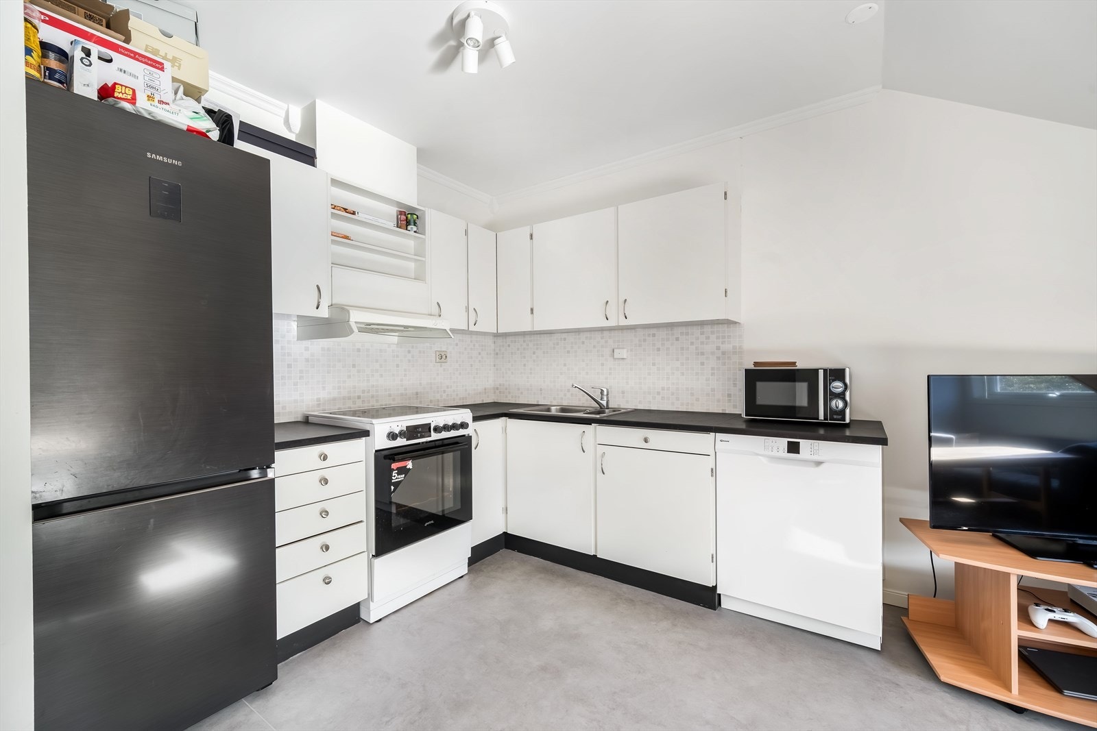 Lys kjøkkeninnredning med mørk benkeplate.' Galleribilde