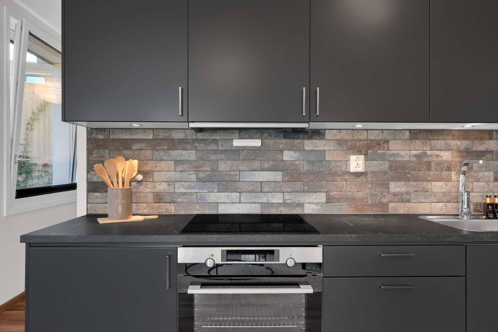 Flislagt vegg over kjøkkenbenk, to doble stikkontakter og led bernkebelysning under overskap Galleribilde