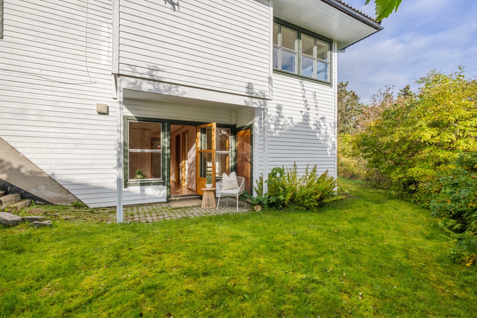 Hage på siden av boligen, hvor det er inngang til stue i underetasjen Galleribilde