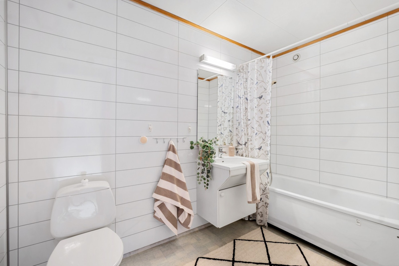 Bad i underetasjen med baderomsplater på vegg og vinylbelegg med varmekabler i gulvet. Innredning med nedfelt servant, toalett og badekar. Galleribilde