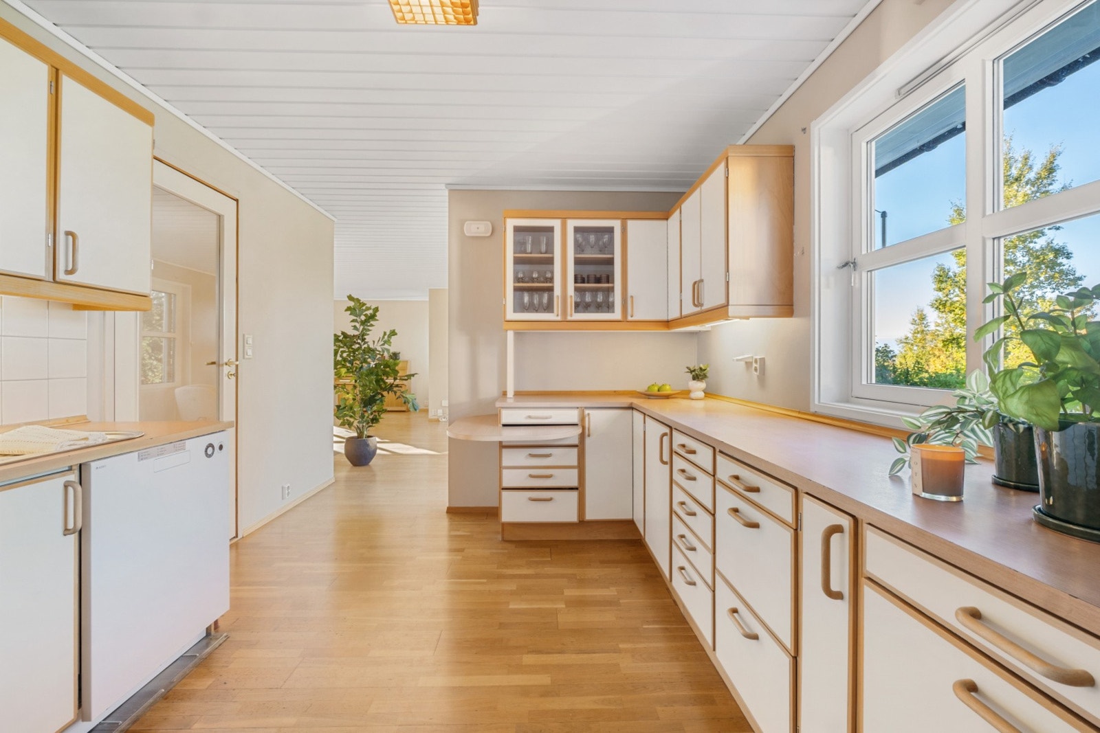 Lyst kjøkken, utstyrt med oppvaskmaskin og frittstående komfyr. Galleribilde