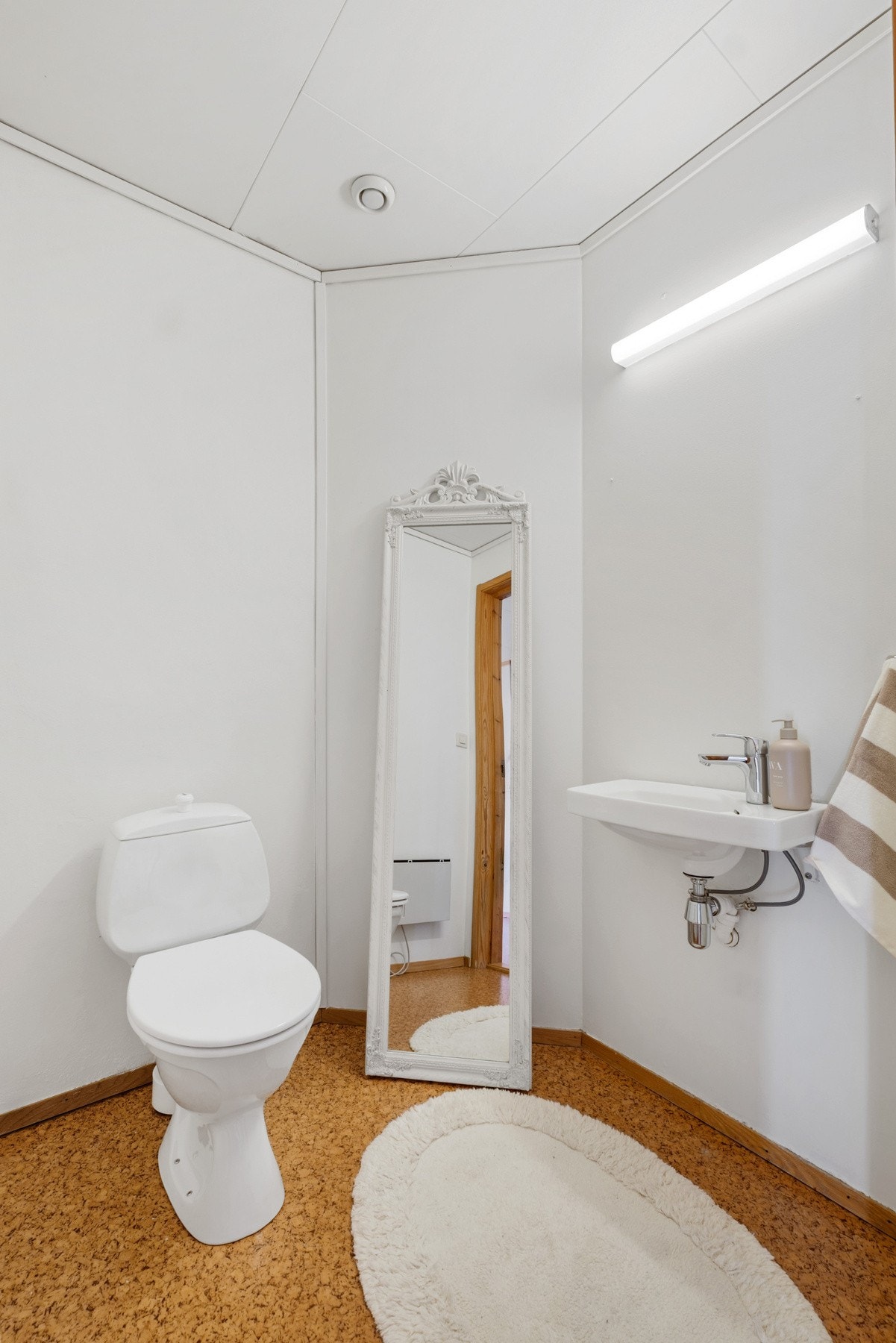 Toalettrom i gang med gulvstående toalett og vegghengt servant Galleribilde