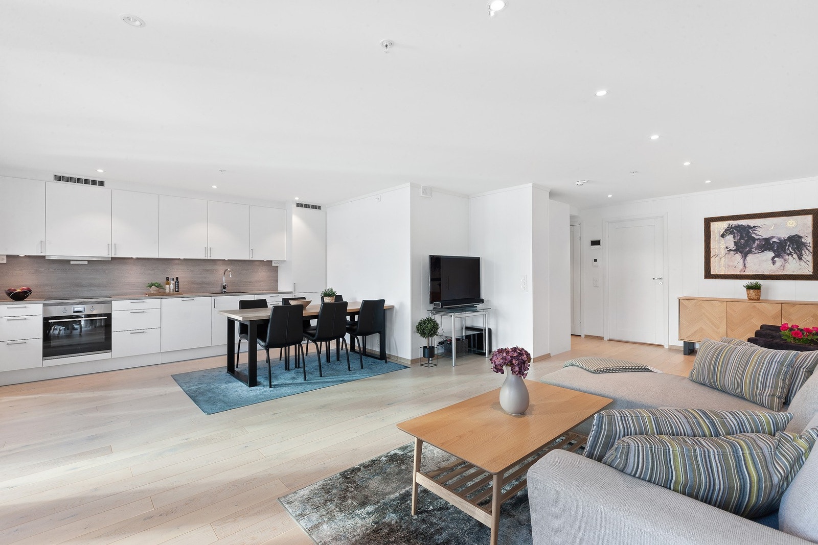 Stue og kjøkken i åpen løsning gir god romfølelse og naturlig flyt mellom sonene. Galleribilde