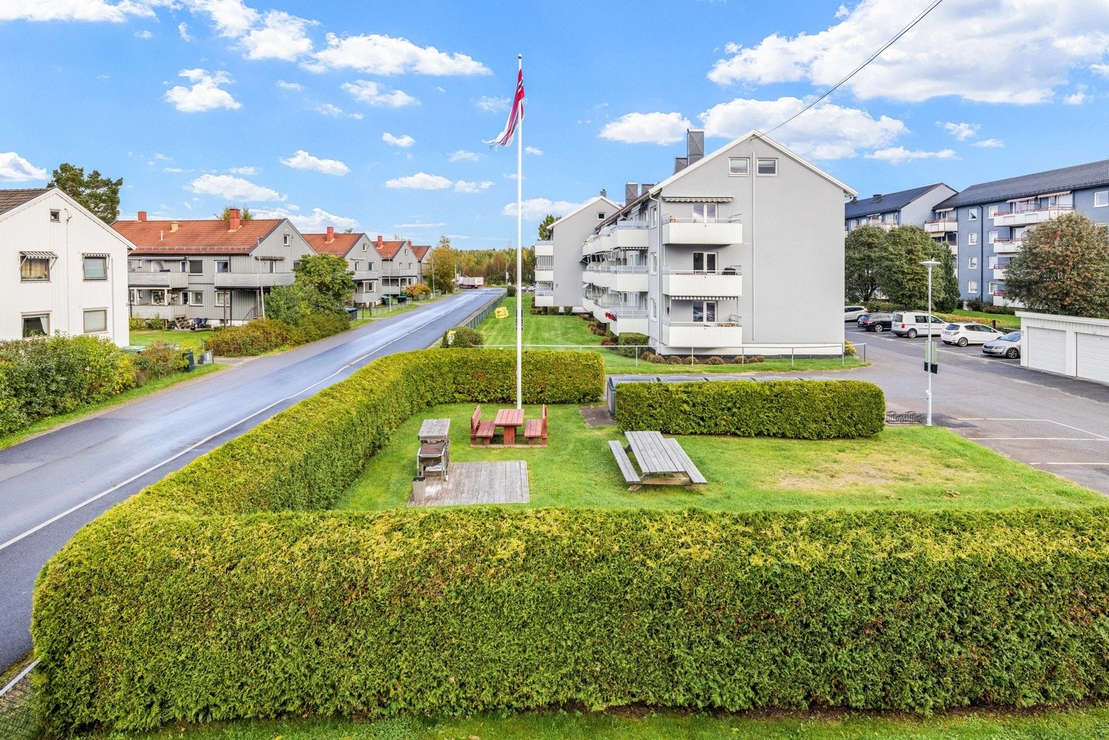 Avskjermet grøntareal med tett hekk, flaggstang og sittebenker til beboerne. Galleribilde