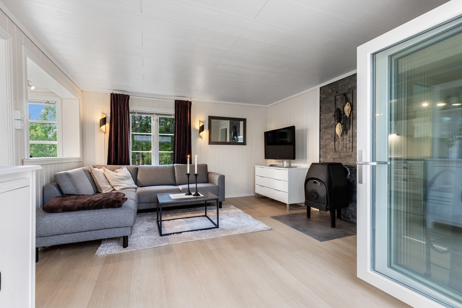 En glasskyvedør gir masse naturlig lys inn i stuen, som gjenspeiles på de hvite veggene. Galleribilde