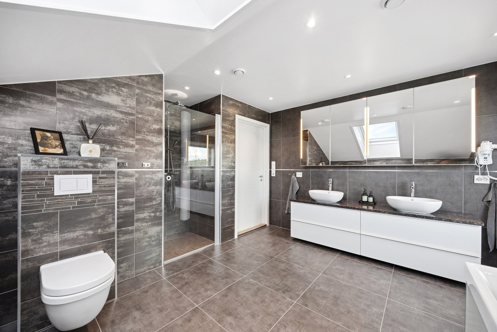 Badet er utstyrt med en lekker innredning med 2 servanter, dusjnisje, veggmontert toalett og badekar med bobler. Galleribilde