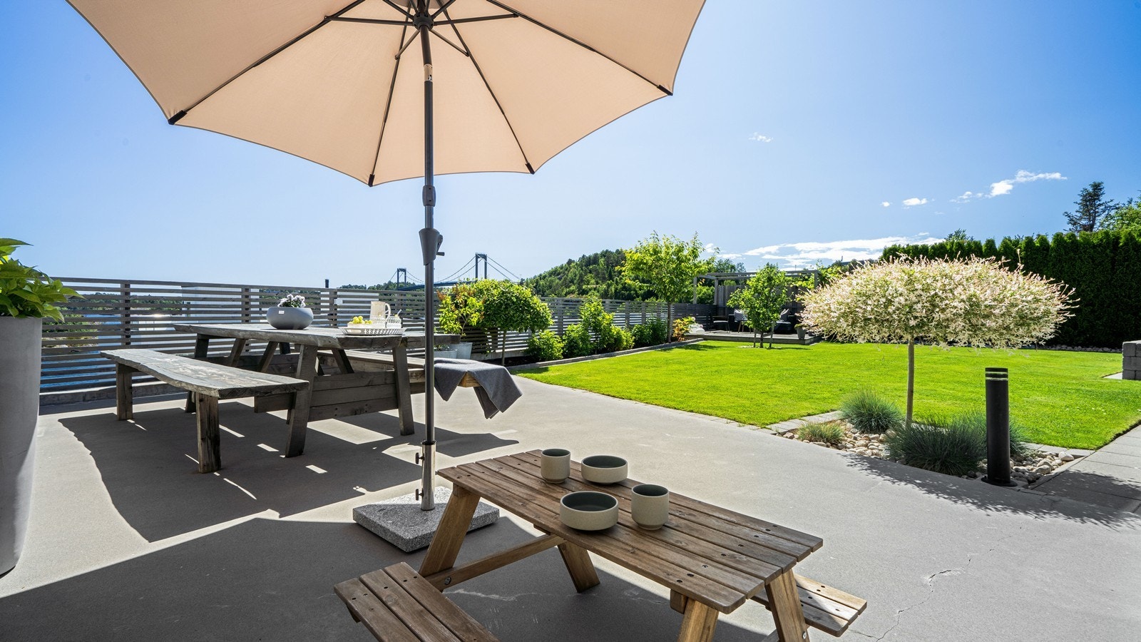 Boligen har en nydelig og pent opparbeidet tomt med gress, beplantning og fine terrasseområder Galleribilde