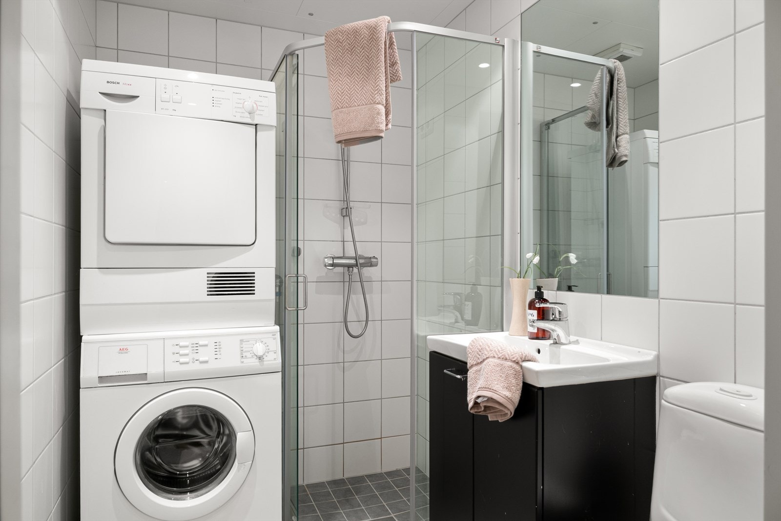 Badet er innredet med servant i møbel, toalett, dusjhjørne, og opplegg for vaskemaskin. Galleribilde