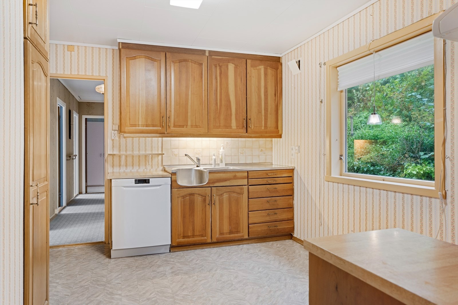 Boligen har et eldre kjøkken med kjøkkeninnredning i mørk eik og laminat benkeplate Galleribilde