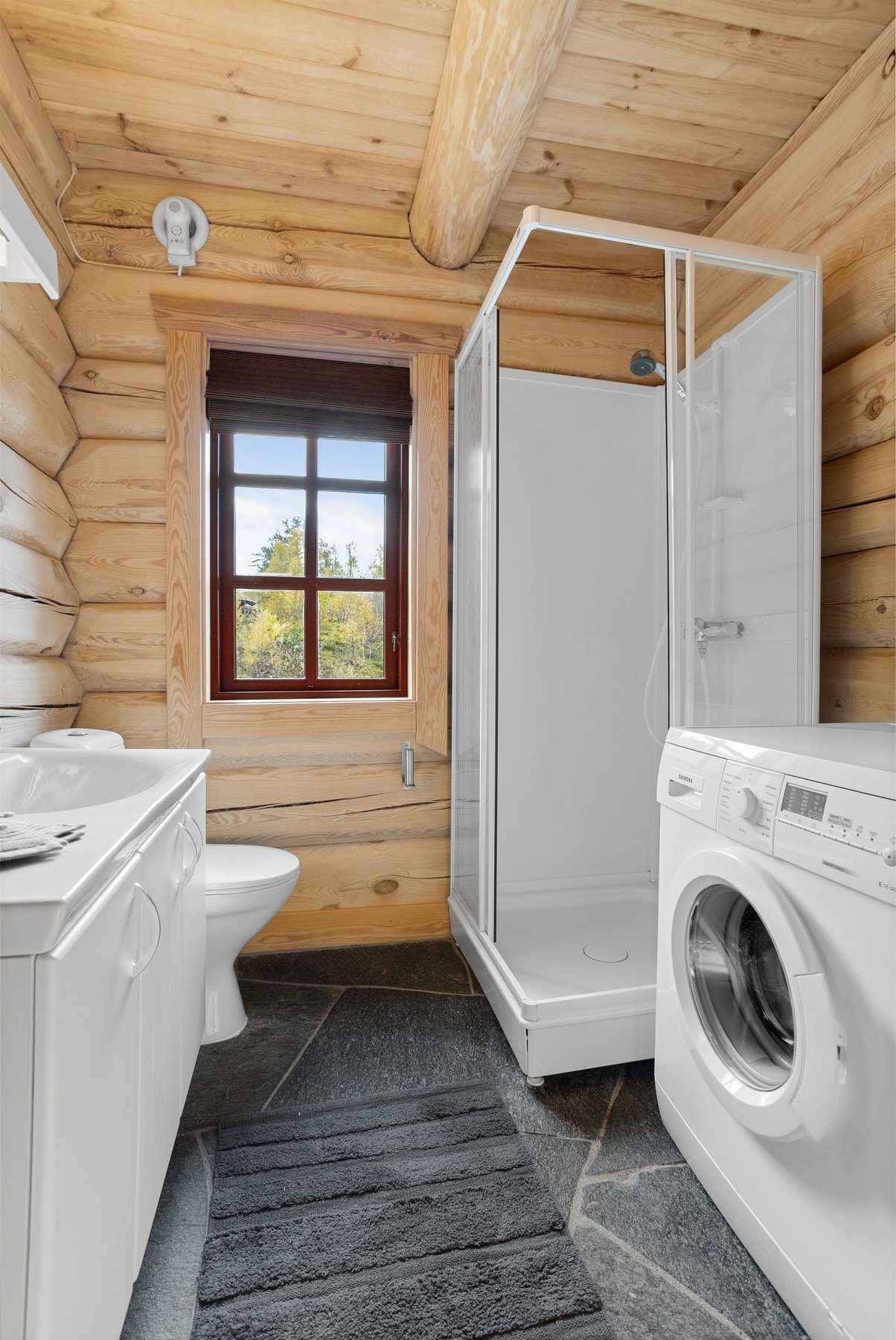 Badet inneholder servant i innredning, dusjkabinett, toalett, vaskemaskin og inngang til badstue Galleribilde