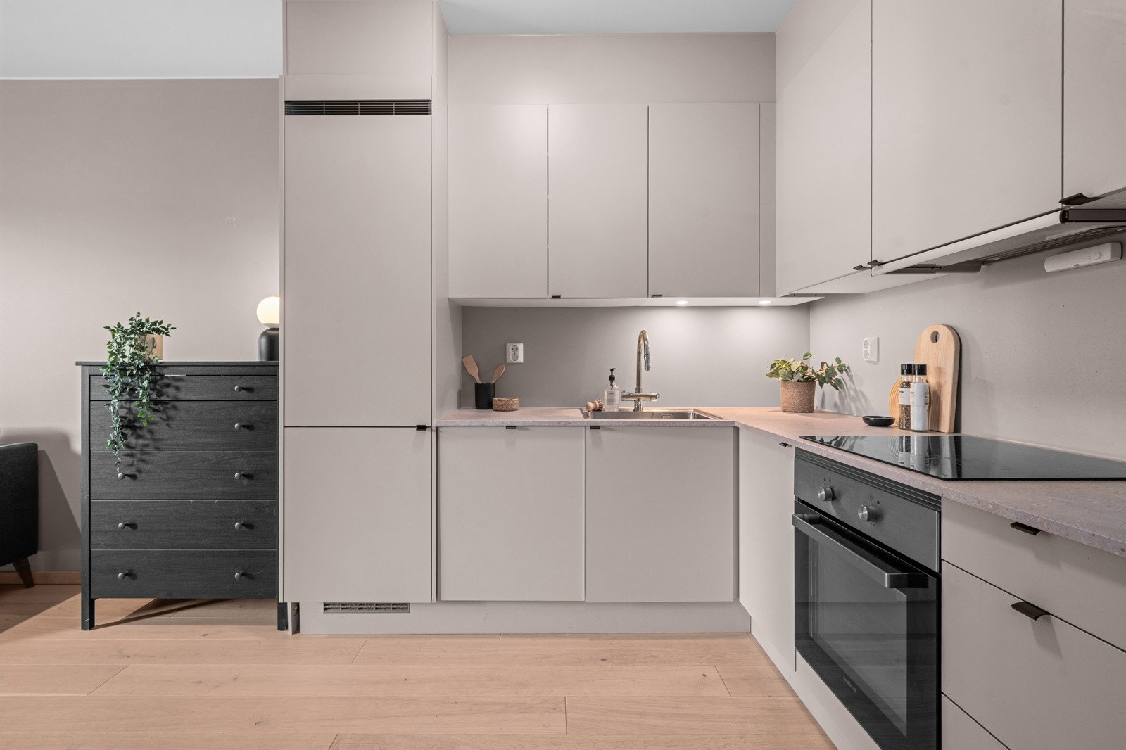 Kjøkkenet er velutstyrt med takhøye skap, integrerte hvitevarer og benkeplate i laminat Galleribilde