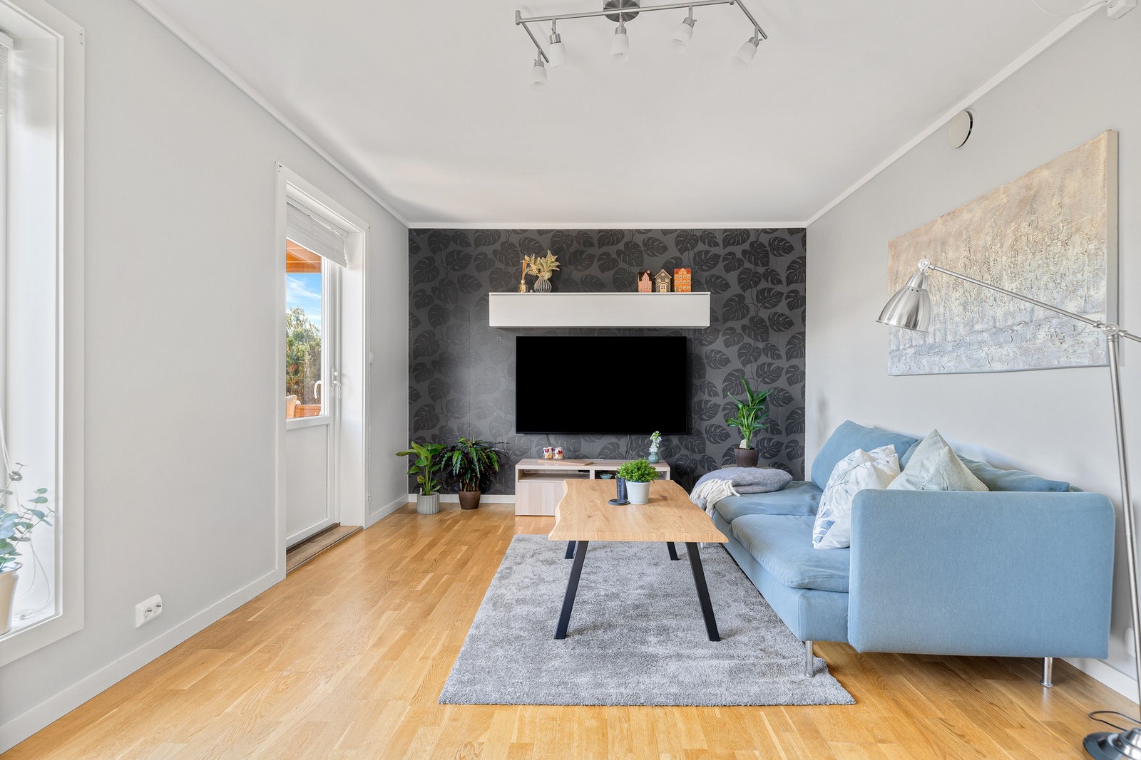 Én vegg i stuen er kledd med en mønstret tapet i fin kontrast. Galleribilde