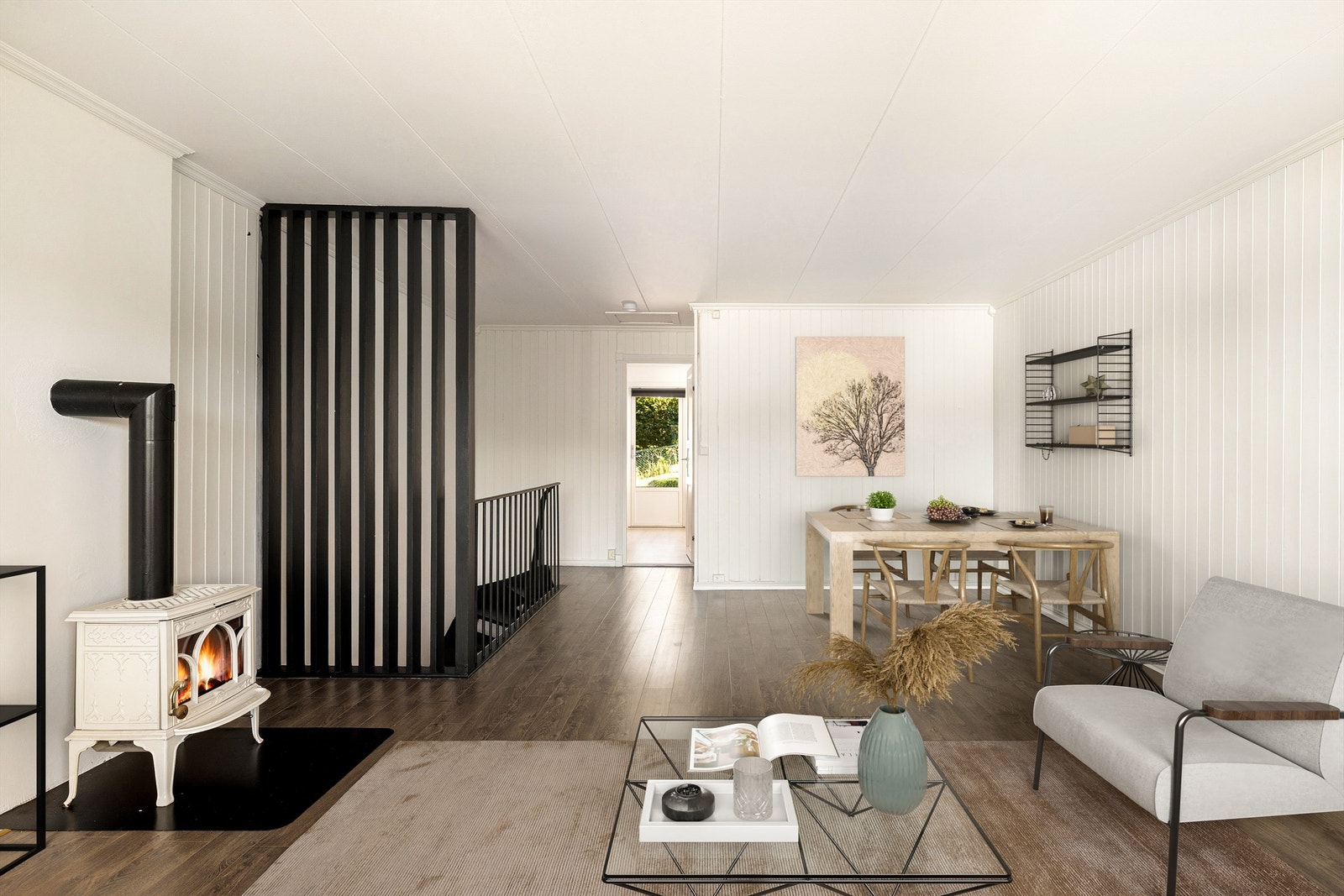 Stuen har rikelig med dagslys, mørke laminatgulv og fyringsmuligheter i vedovn. Bildet er digitalstylet. Galleribilde