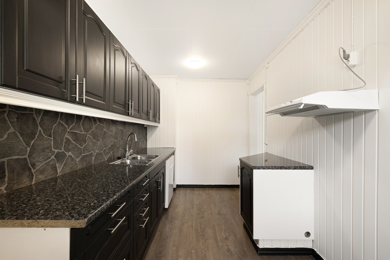 Kjøkkenet har mørke overflater, og rikelig med oppbevaring i overskap. Galleribilde