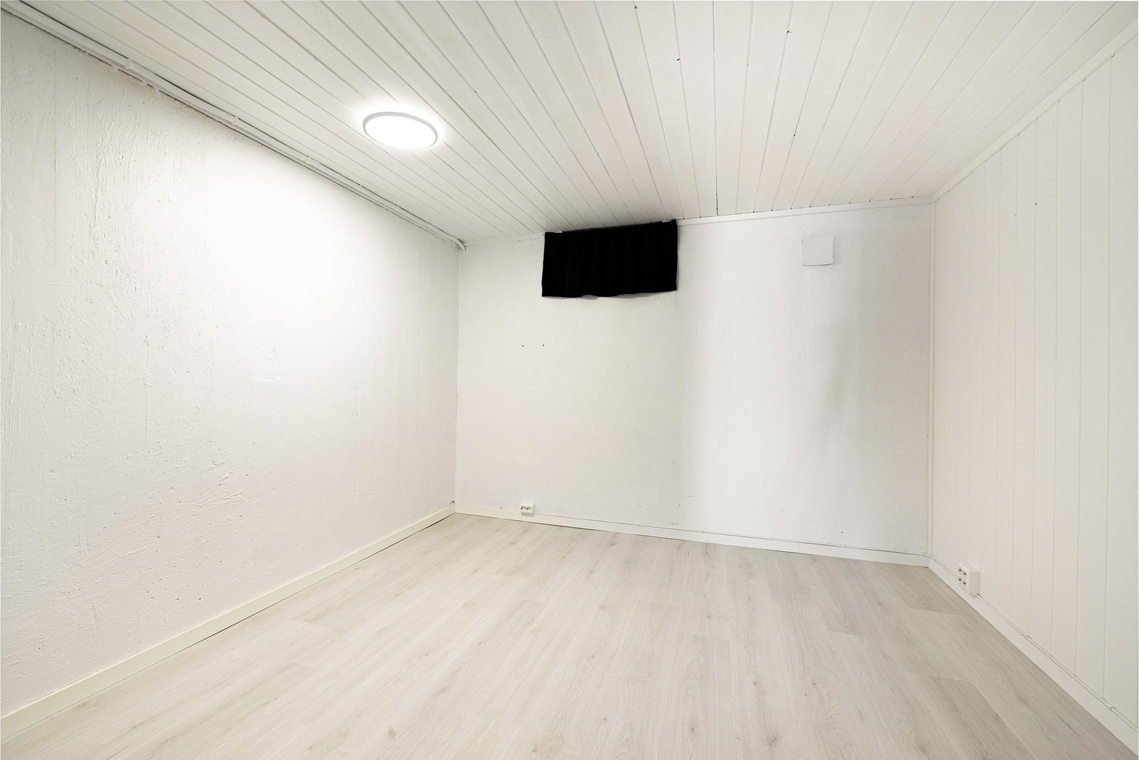 Kompakt kjellerrom med lyse vegger og gulv. Brukes i dag som bod. Galleribilde