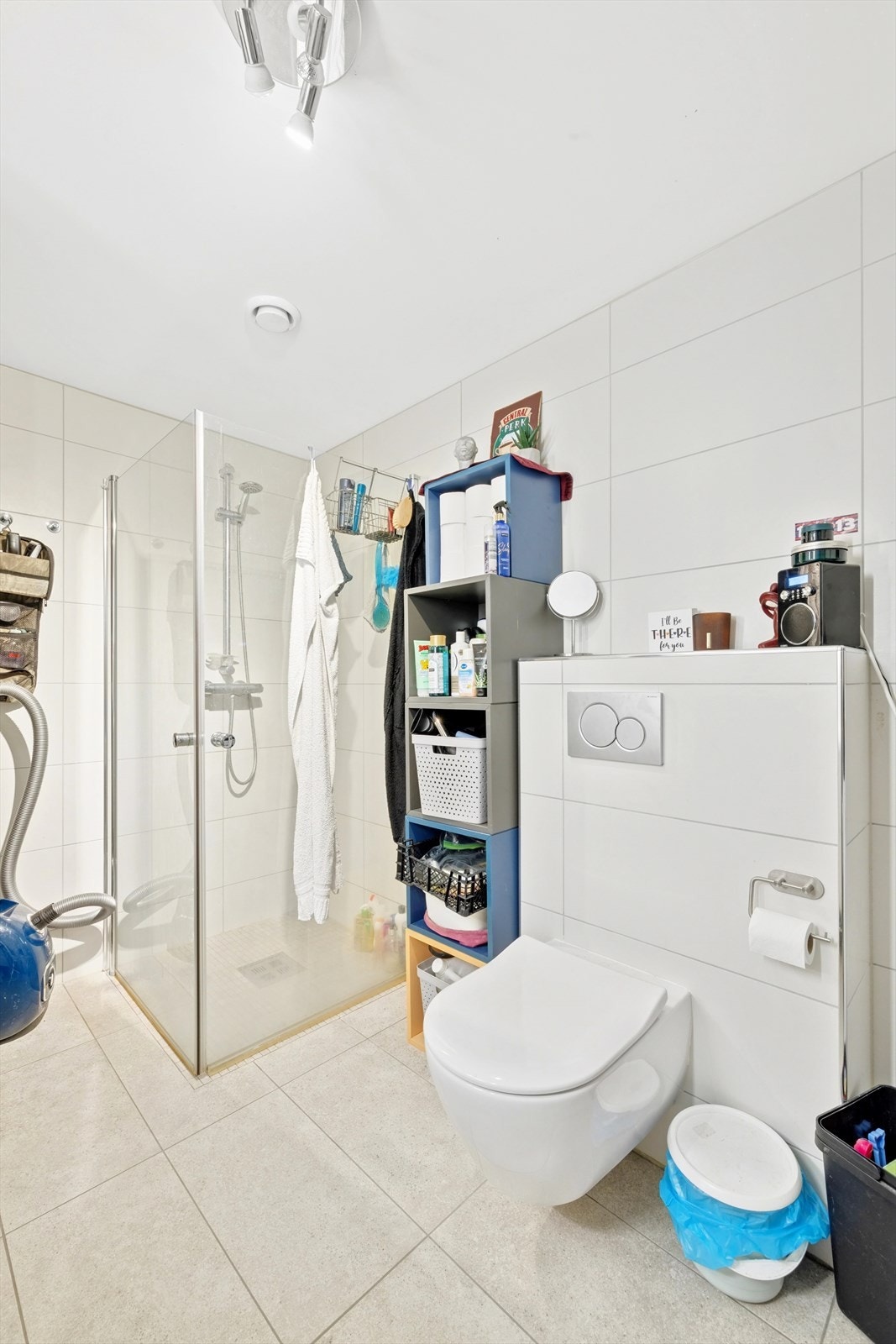 Flislagt baderom. Støpt gulv med vannbåren varme. Innfellbare dusjdører, vegghengt toalett og servant med skuffer. Opplegg for vaskemaskin. Galleribilde