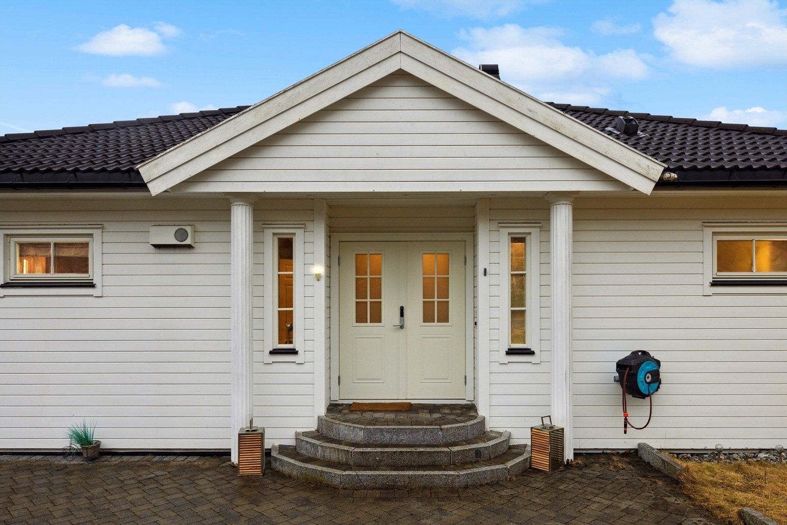 Overbygget inngangsparti. Det er solide søyler som holder takutstikket oppe. Galleribilde