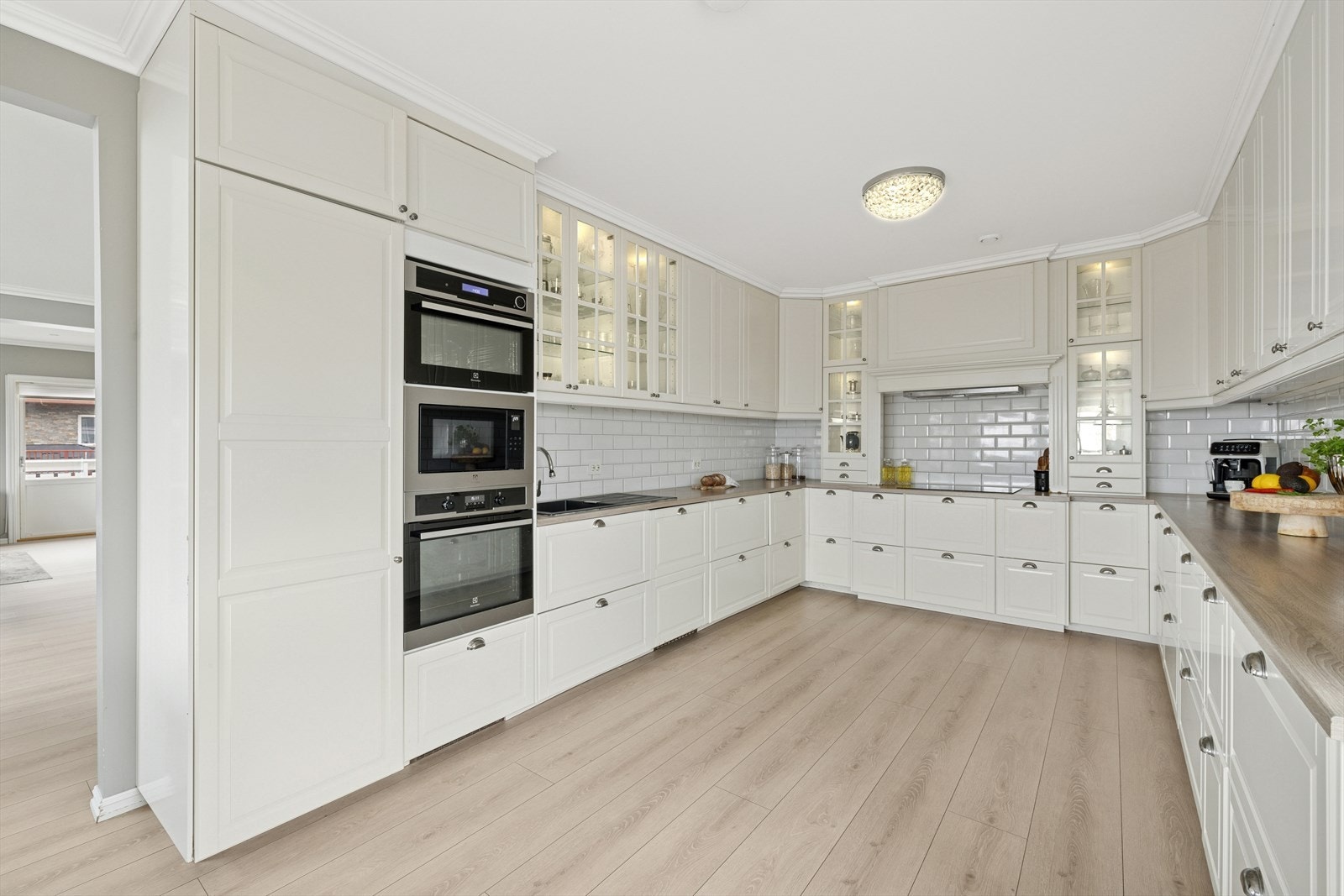 Kjøkkeninnredning har profilerte fronter og flere glassdører med belysning i overskapene. Galleribilde