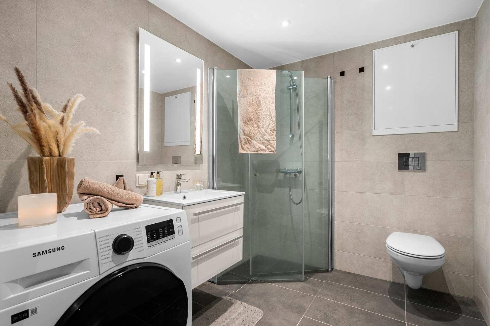 Flislagt bad med downlights i tak og lys i speil. Det er også opplegg for vaskemaskin på badet. Galleribilde