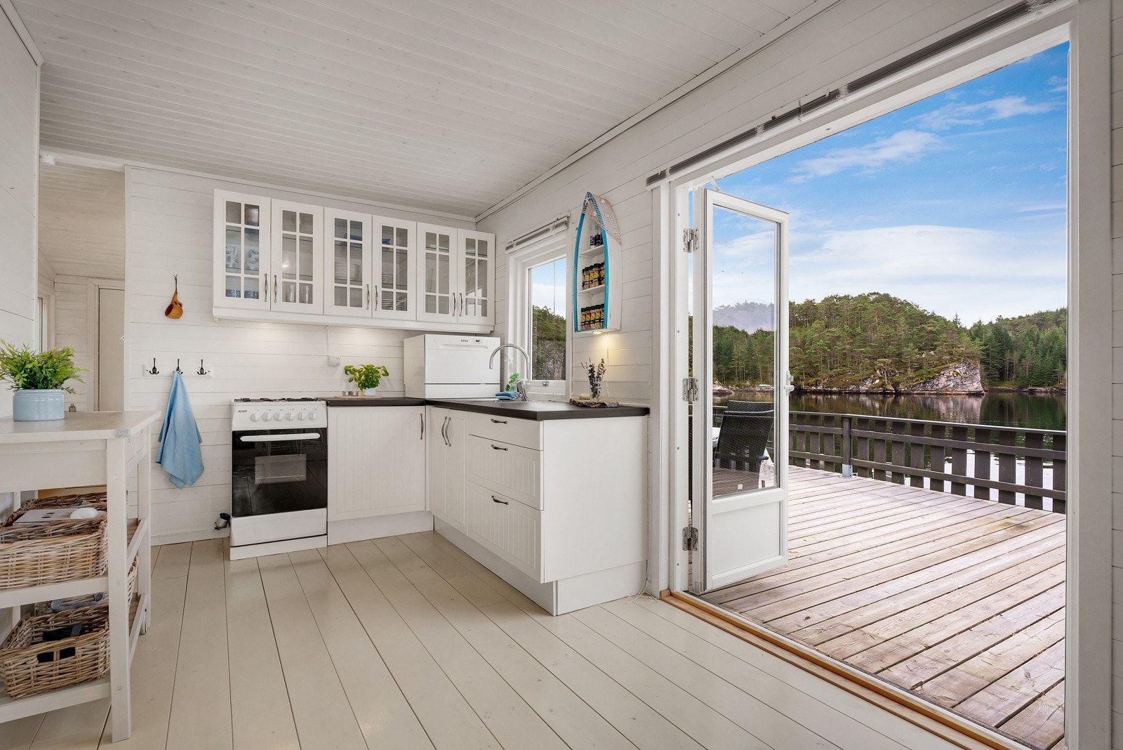 Tidløs kjøkkeninnredning med hvite fronter og laminat benkeplate. Her kan man nyte den nydelige utsikten mens man kokkelerer! Galleribilde