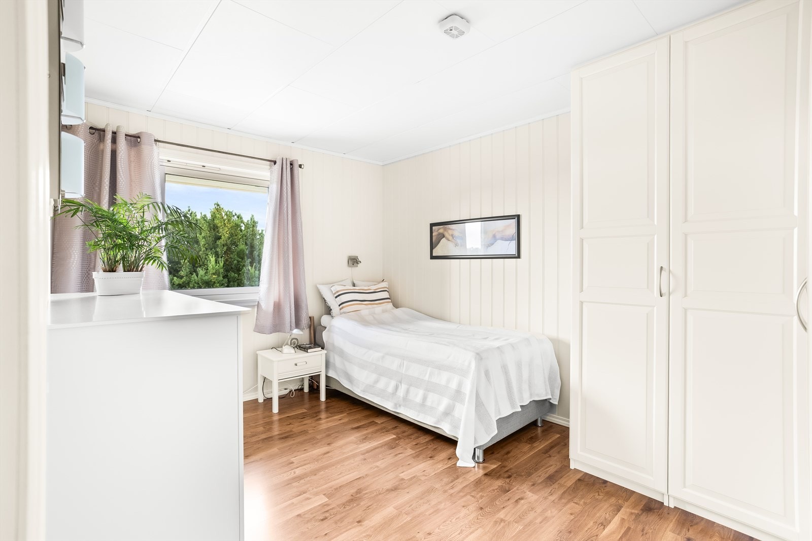 To lyse og fine soverom som begge har store vinduer og panelte overflater. Galleribilde