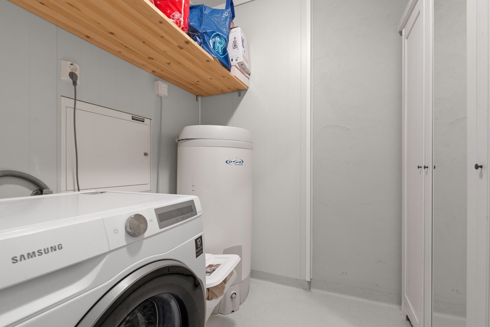 Vaskerom fra byggeår. Vinylbelegg på gulv. Mdf-panel på vegger. Rommet er innredet med vaskemaskin og varmtvannsbereder. Galleribilde