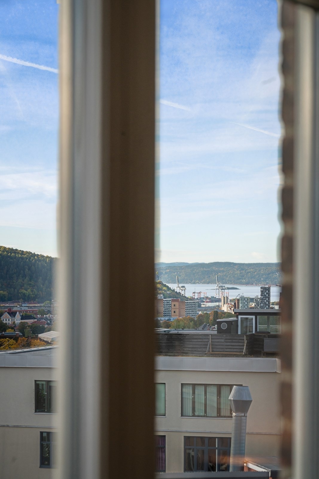 Bygget ligger på en høyde og leiligheten har hyggelig utsikt over hustakene og til fjorden. Galleribilde