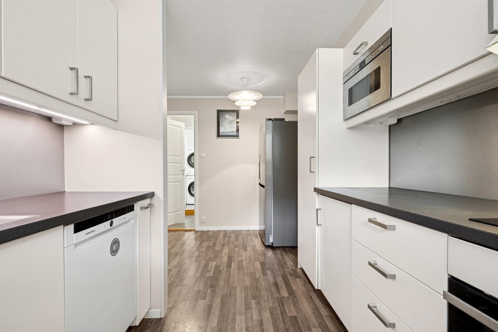 Kjøkkenet er ellers utstyrt med kjøleskap, oppvaskmaskin, stekeovn, mikrobølgeovn, koketopp og kjøkkenventilator med mekanisk avtrekk i boenheten/bygget. Galleribilde