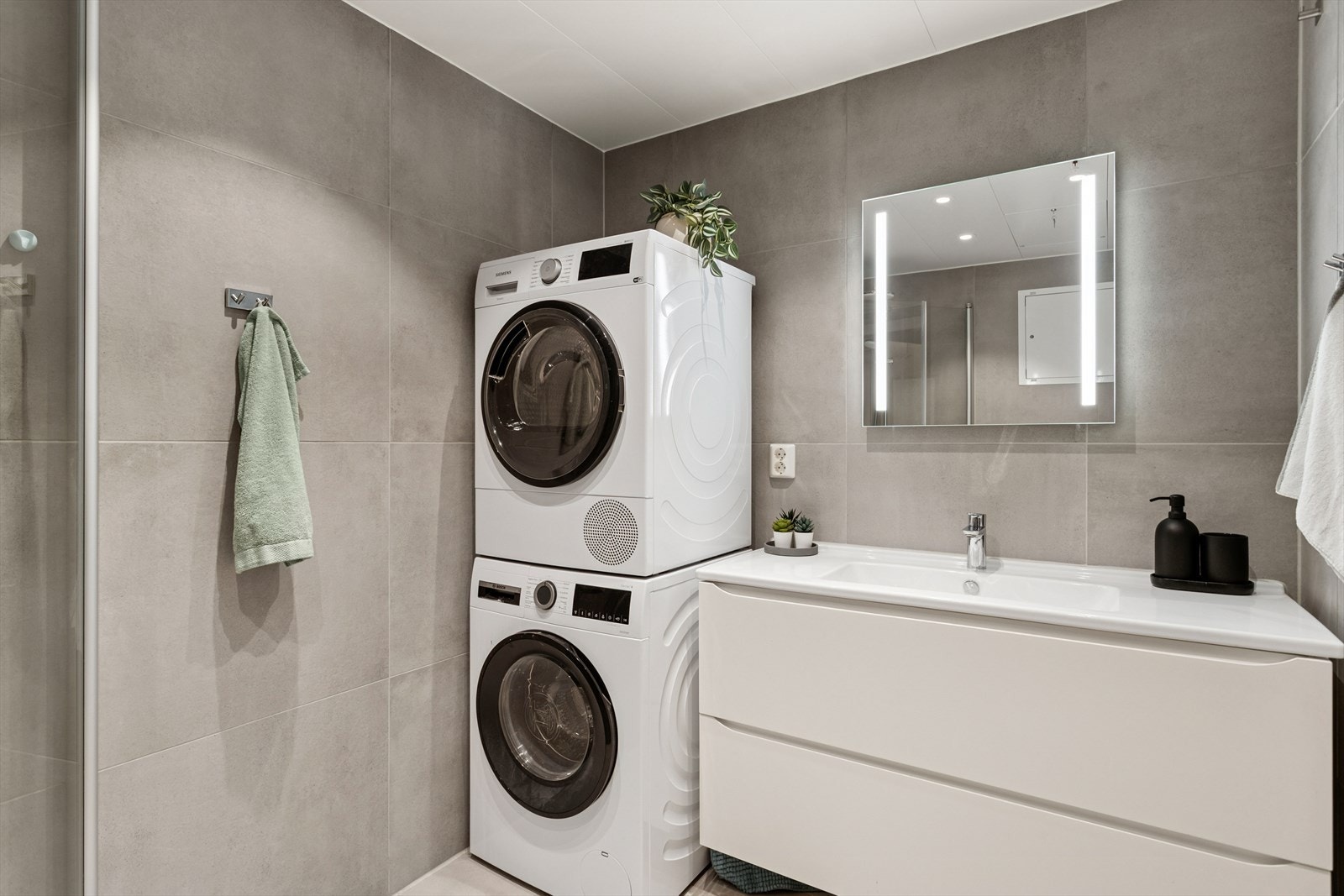 Badet har dusjvegger av glass, vegghengt toalett, innredning med servant samt opplegg for vaskemaskin. Overflatene har liten slitasje og framstår i god bruksmesssig stand. Galleribilde