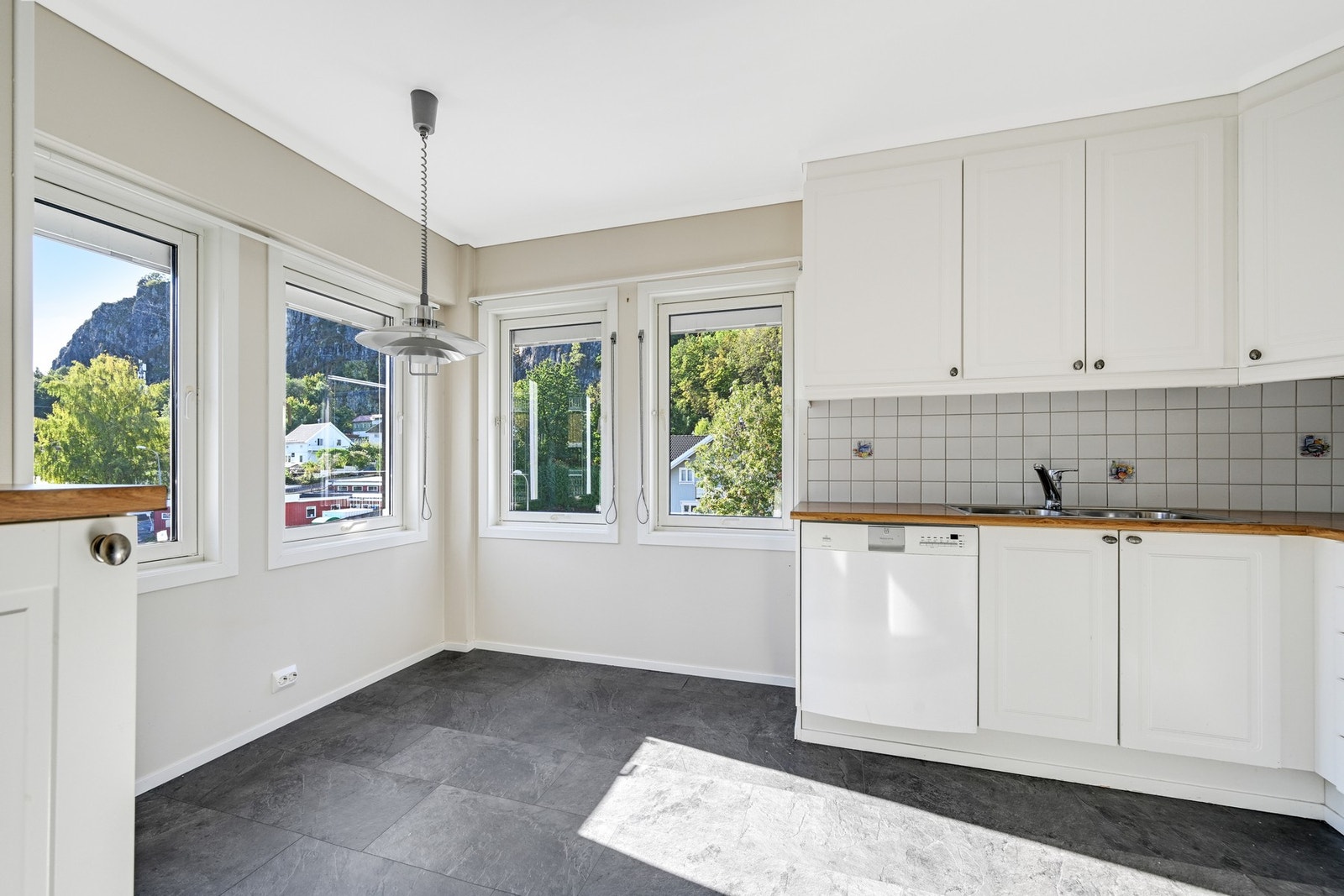 Det er fliser over benken, og en justerbar taklampe sørger for belysning. Oppvaskmaskin, komfyr og kjøle/fryseskap medfølger handelen. Galleribilde