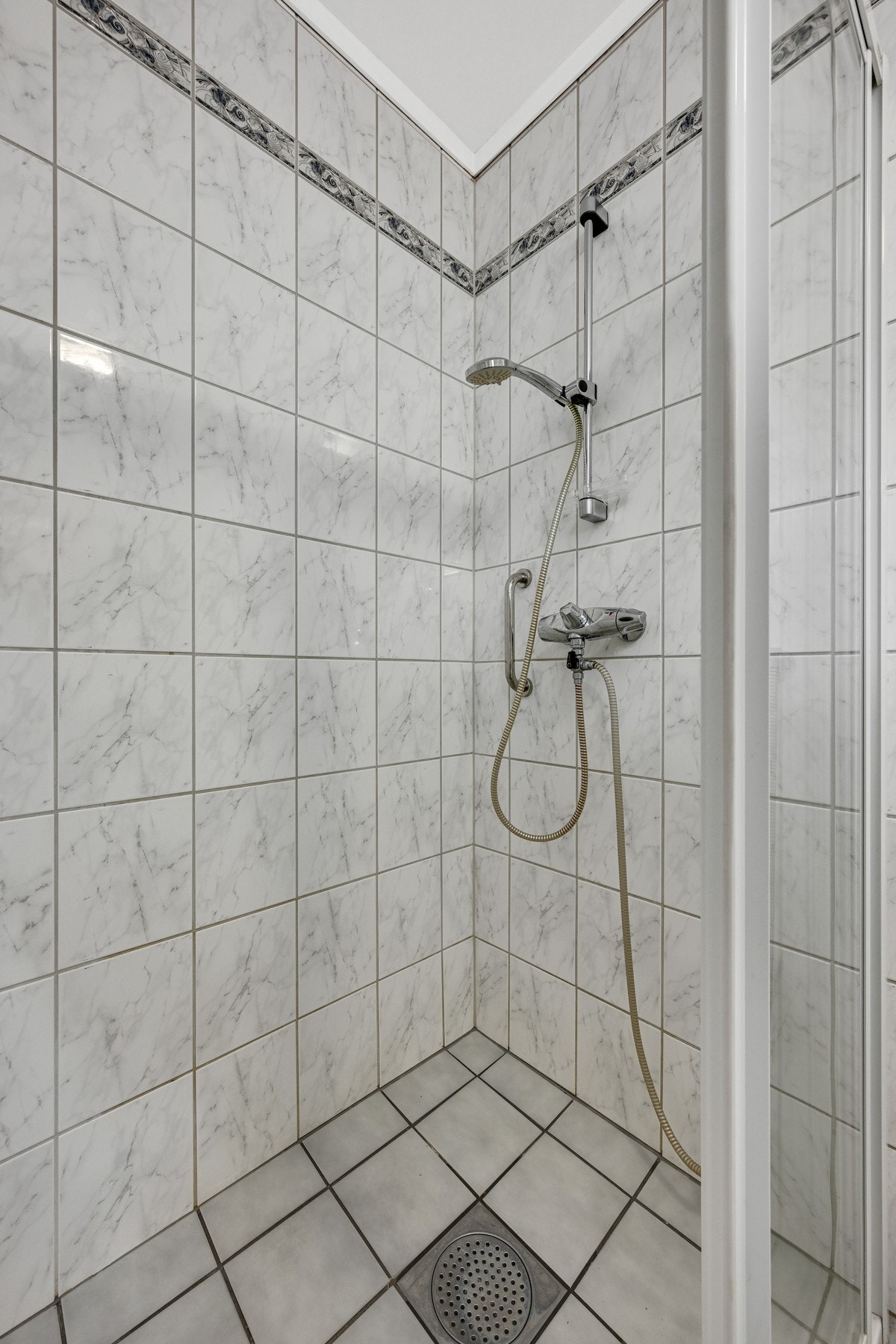 Dusjhjørne med fliser på vegger og gulv, dusjhode og blandebatteri. Galleribilde