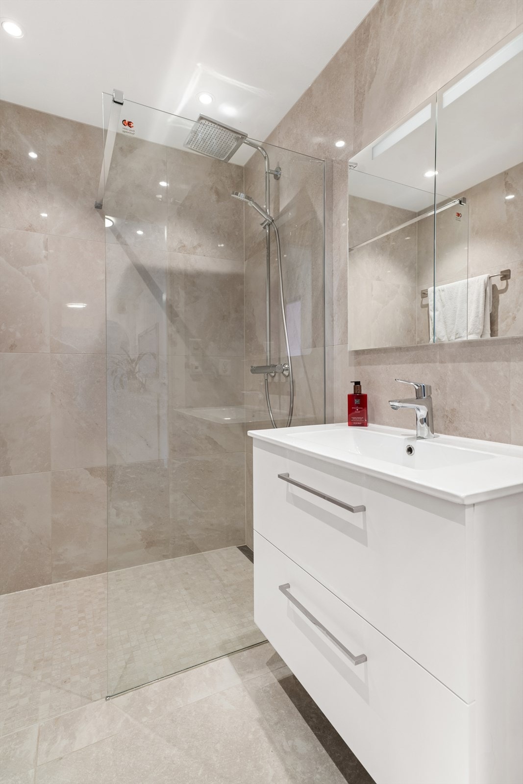 Badet er utstyrt med dusjhjørne med glassvegg, samt baderomsinnredning med nedfelt servant. Galleribilde