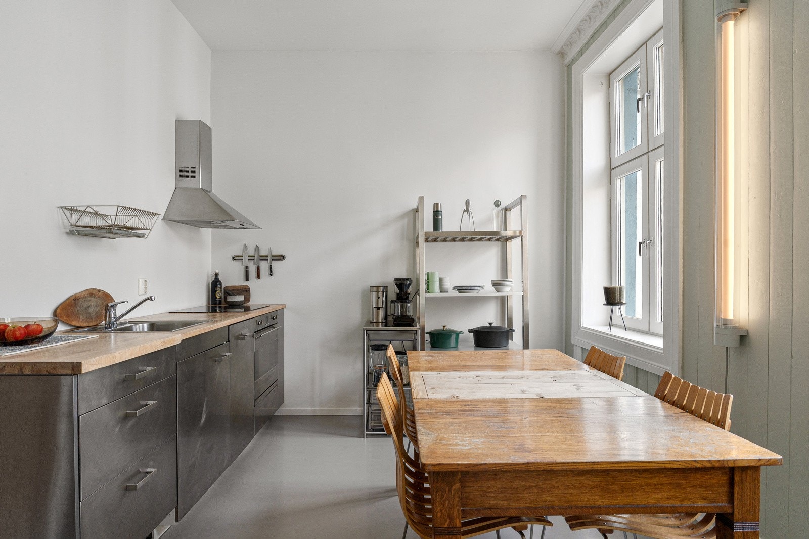 Moderne kjøkkeninnredning med stålfronter, intergrerte hvitevarer og benkeplate i heltre. Galleribilde