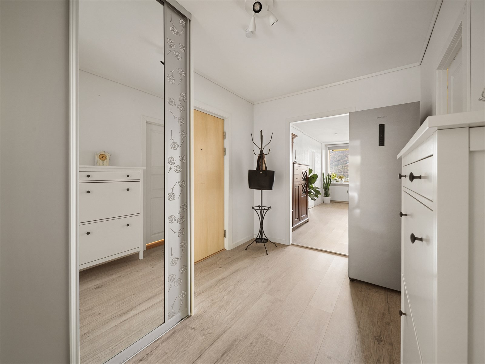 Velkommen inn i en romslig entrè med god plass til å henge fra seg yttertøy og sko. Det er innredet med en stor skyvedørsgarderobe med speilfronter. Galleribilde