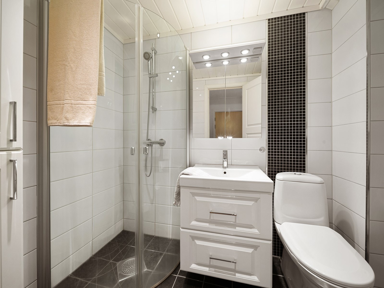 Pent helfliset bad innredet med baderomsinnredning med servant, toalett, dusj og opplegg for vaskemaskin. Galleribilde