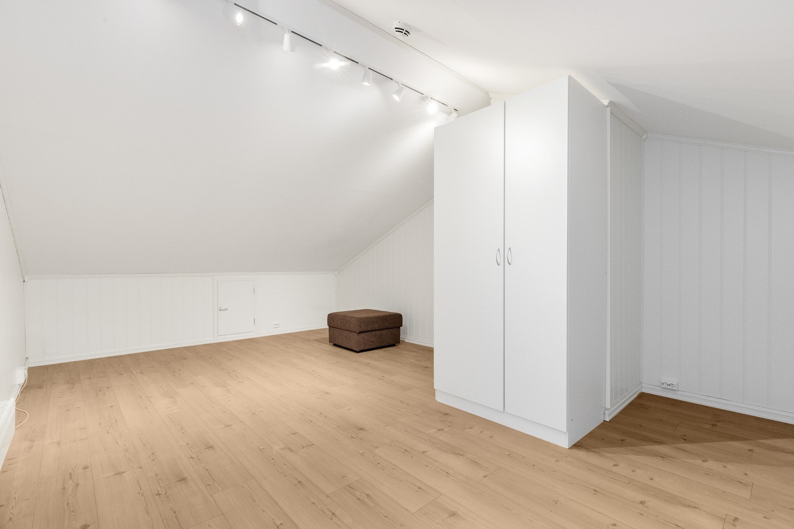 Romslig loft med laminat på gulv, og vegg og himling er kledd med plater. Galleribilde