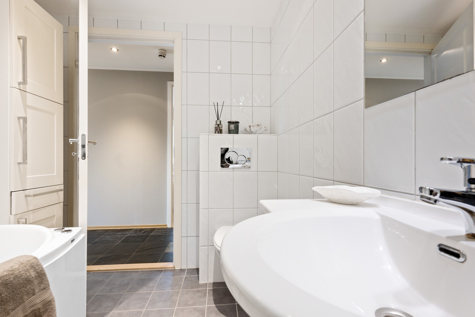 Badet har fliselagt gulv og vegger og malt himling med downlights. Galleribilde