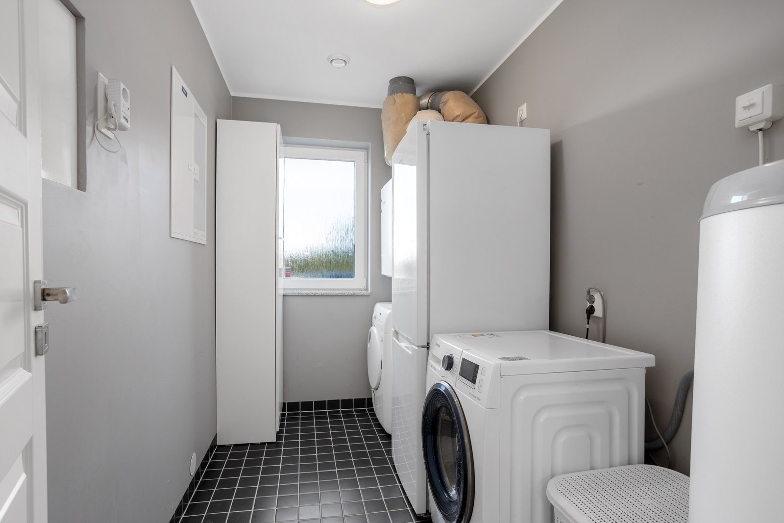 Praktisk vaskerom. Flislagt gulv med sluk, opplegg for både vaskemaskin og tørketrommel. Galleribilde