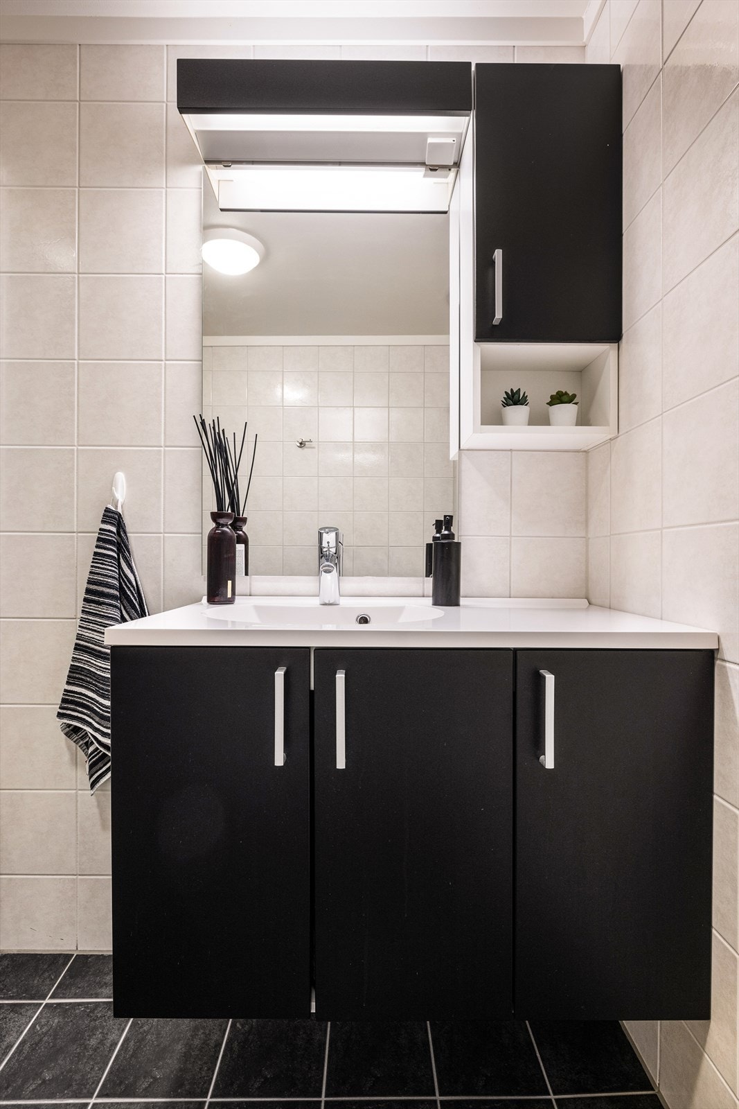 Badet har pen, mørk innredning og speil over vasken Galleribilde