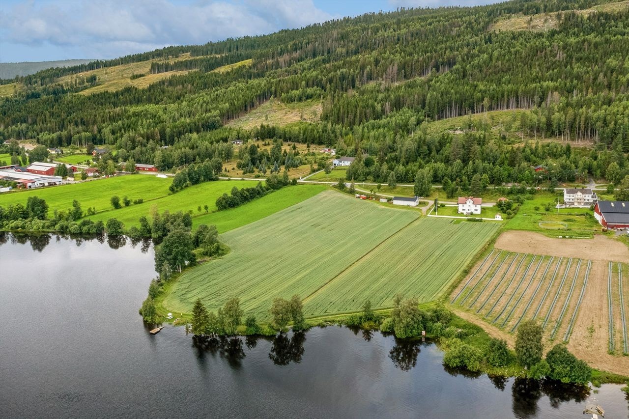 Oversiktsbilde fra øst med dyrket mark mellom gårdstun og Hurdalssjøen Galleribilde