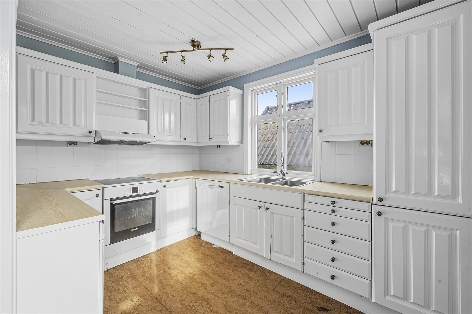 Lyst kjøkken med hvite, profilerte fronter og laminert benkeplate Galleribilde