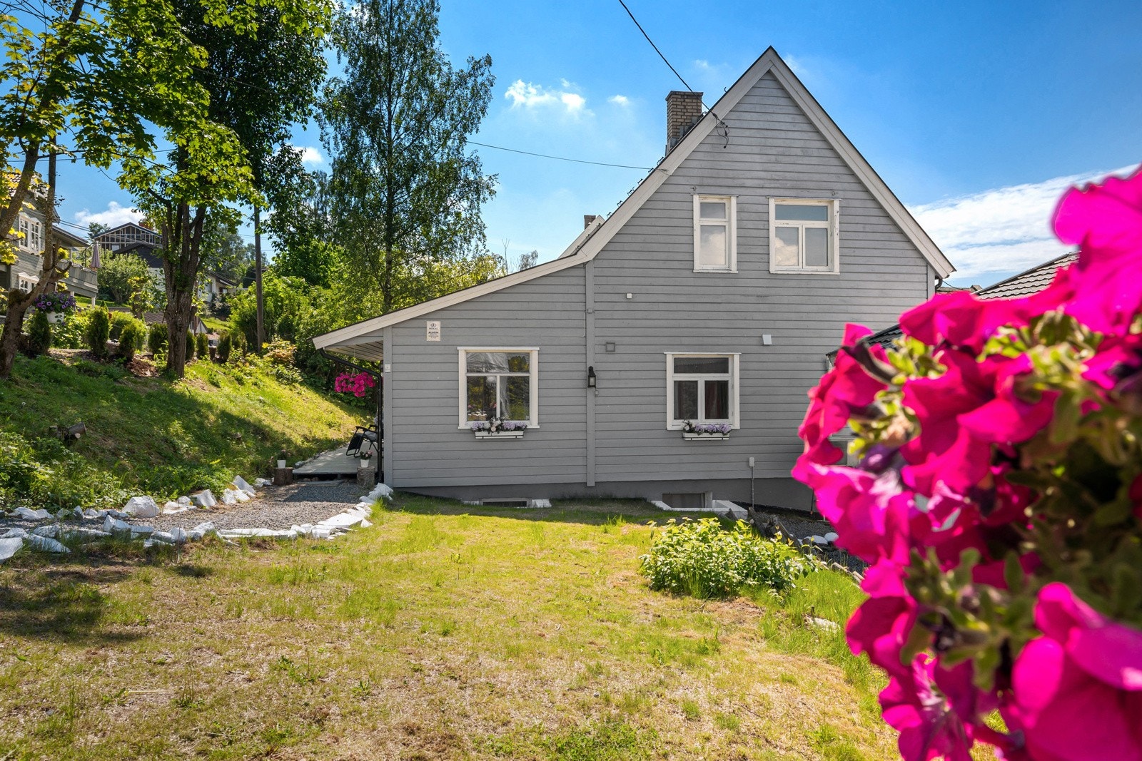Boligen har en lys fasade, med flotte buskevekster Galleribilde