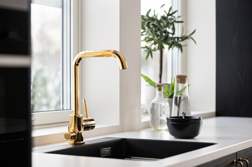 Gullfargede detaljer og en platetopp med integrert ventilator gir kjøkkenet en elegant finish. Galleribilde