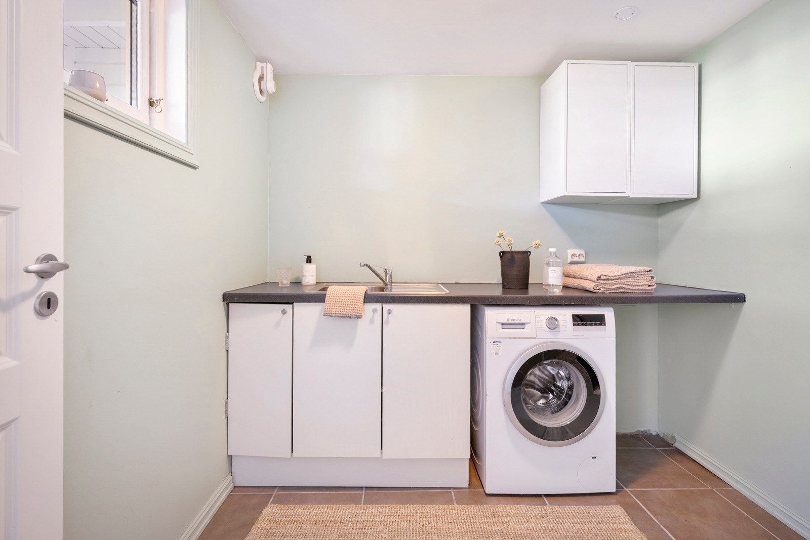 Vaskerommet er plassert like ved og gir en praktisk arbeidsplass med benk, vaskekum og opplegg for både vaskemaskin og tørketrommel. Galleribilde