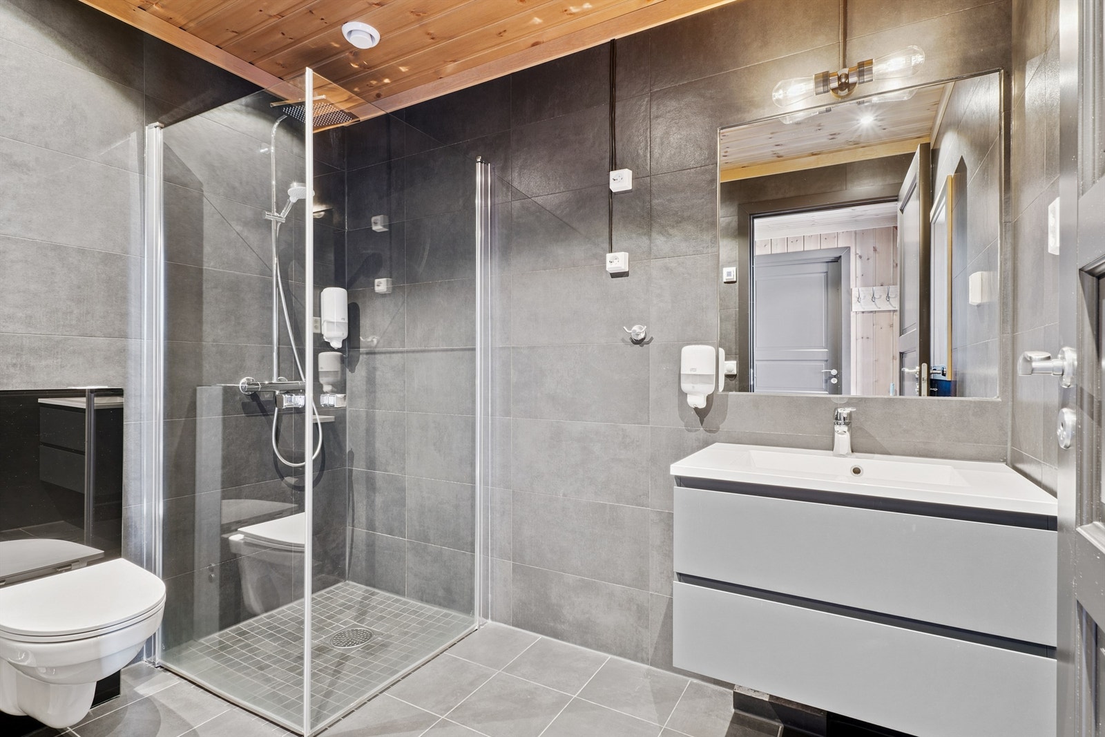 Delikat, flislagt bad med elektriske varmekabler, vegghengt toalett og innfellbare dusjdører. Galleribilde