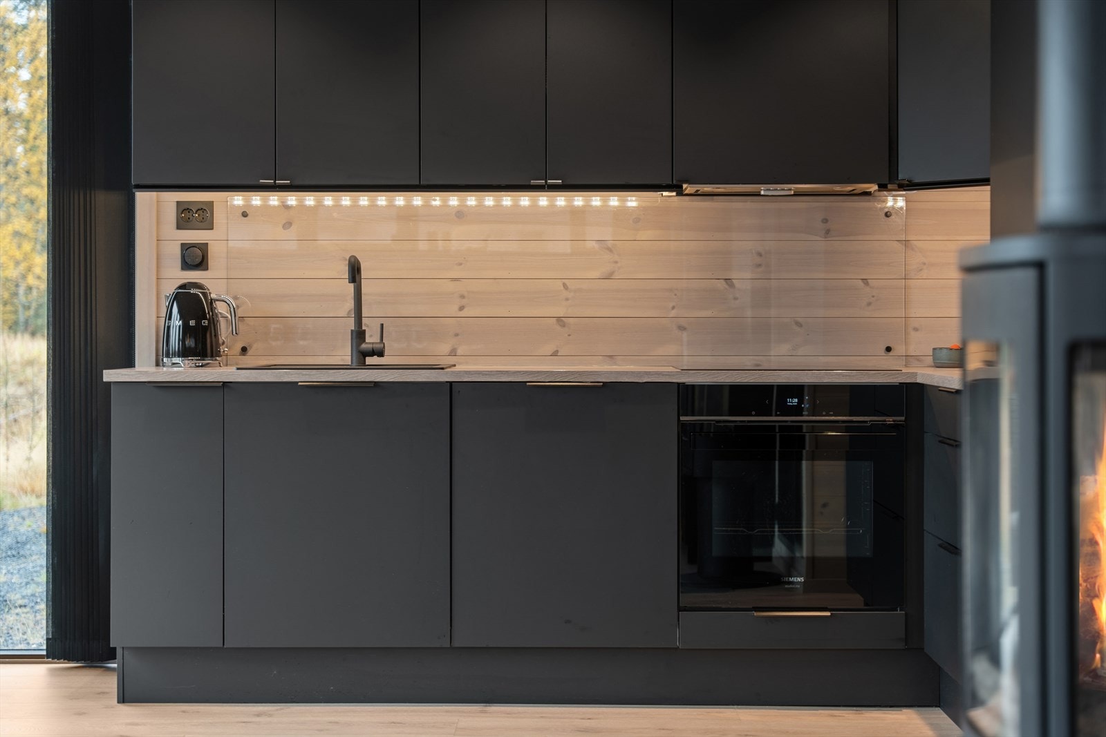 Stilrent kjøkken med sorte MDF-fronter og laminat benkeplate med god arbeidsflate. Den nedfelte komposittkummen gir både funksjon og eleganse. Fullt utstyrt med integrerte hvitevarer og komfyrvakt - en praktisk og trygg løsning med moderne design. Galleribilde