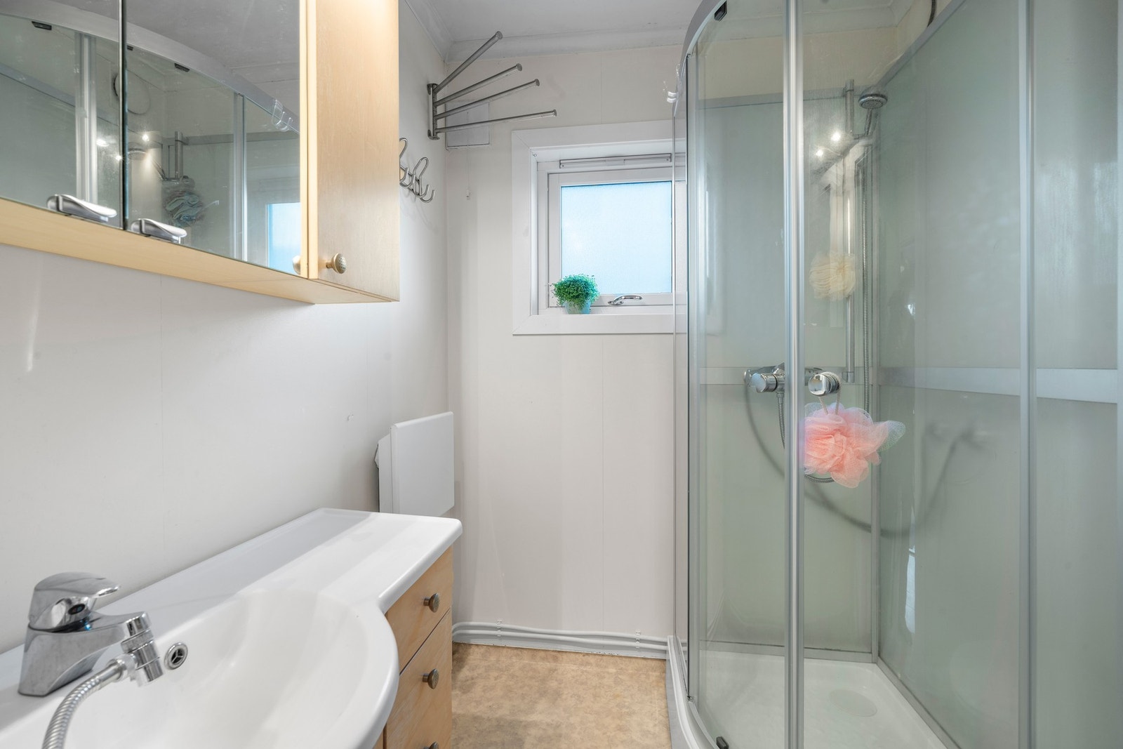 Badet er utstyrt med dusjkabinett, toalett, servant med overspeil og baderomsinnredning. Galleribilde