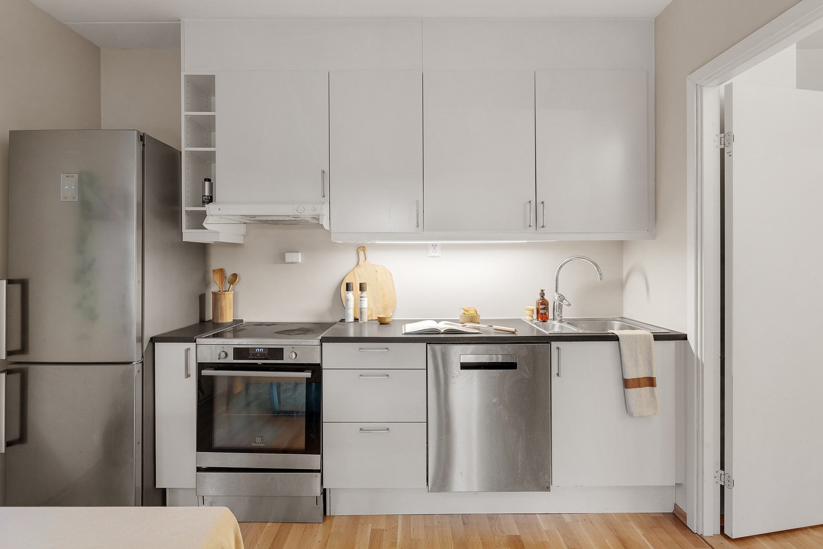 Kjøkkeninnredning med frittstående hvitevarer, slette fronter, laminat benkeplate og ventilator. Galleribilde