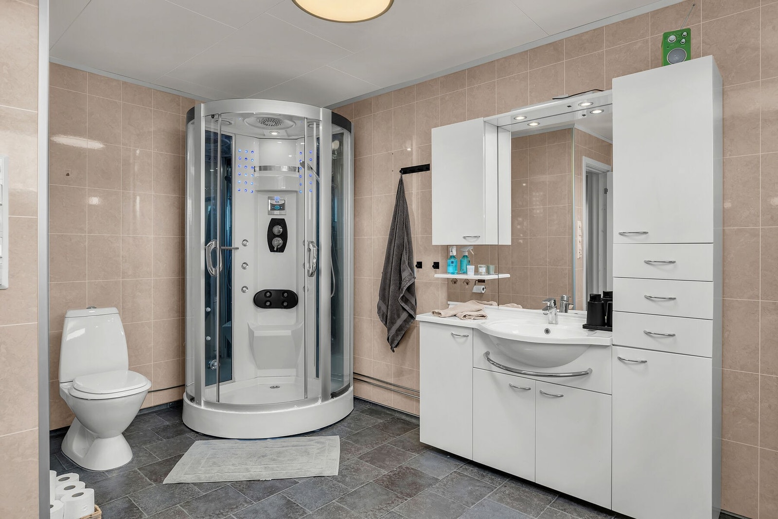 Romslig bad med servant på innredning, dusjkabinett og toalett. Galleribilde