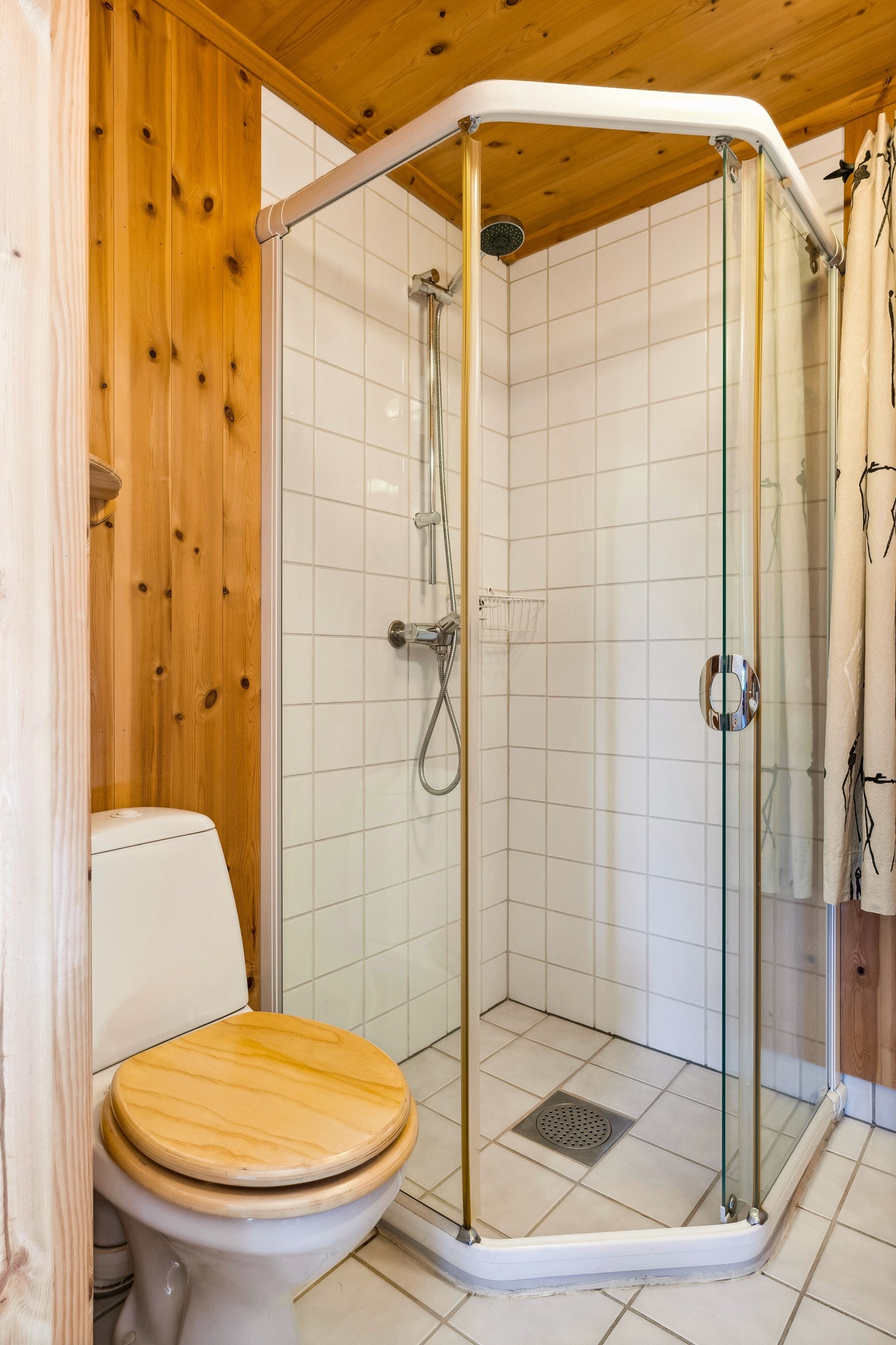 Rommet er enkelt innredet med et gulvmontert toalett, servant med tilhørende speilskap med enkel belysning og en dusjnisje. Galleribilde